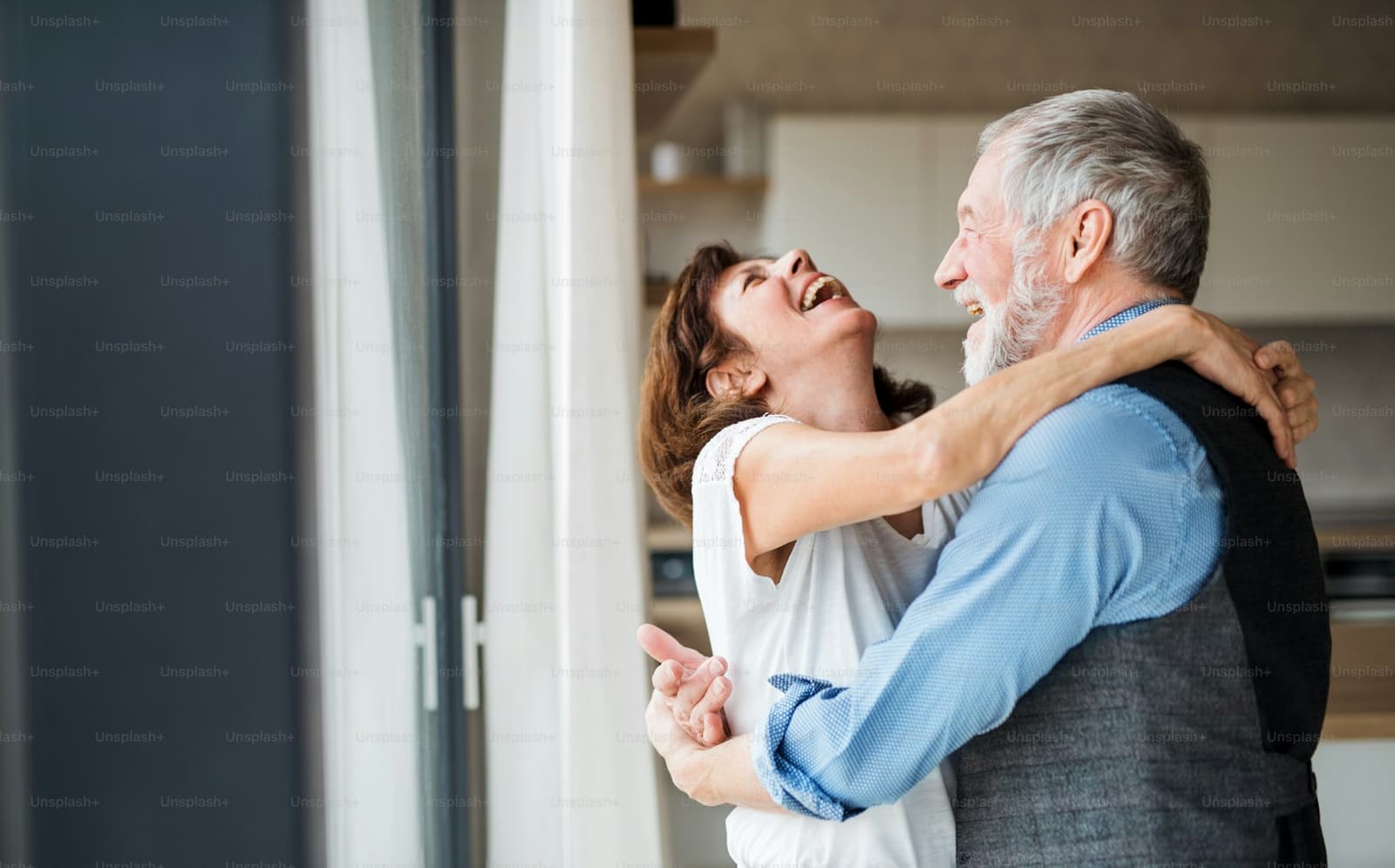 A couple in their sixties laughing together at home